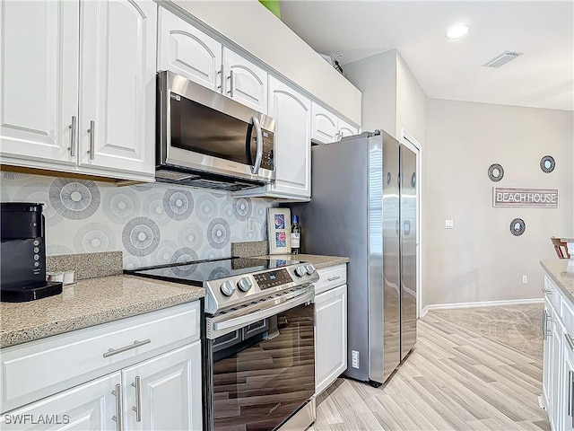 kitchen with stainless steel appliances, light stone counters, decorative backsplash, white cabinets, and light wood-type flooring