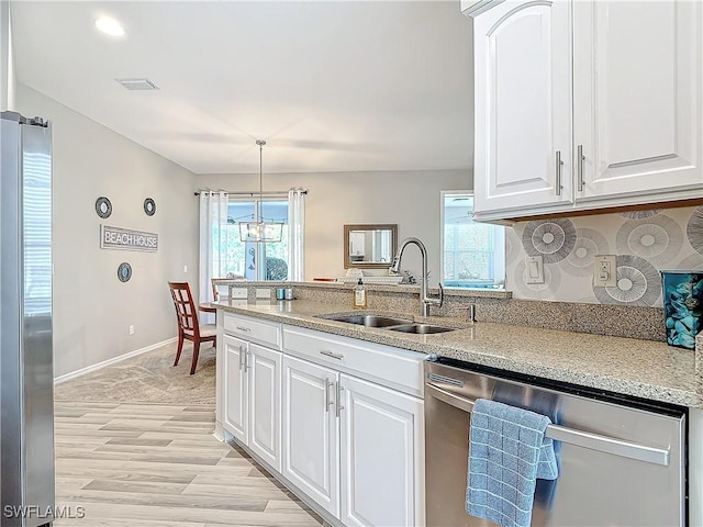 kitchen featuring light stone countertops, stainless steel appliances, sink, white cabinets, and hanging light fixtures