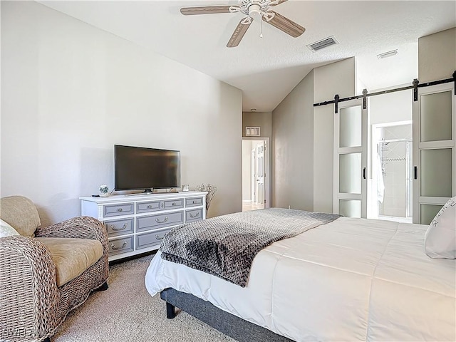 bedroom with connected bathroom, a barn door, ceiling fan, and carpet