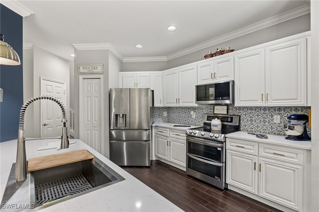 kitchen featuring light stone countertops, appliances with stainless steel finishes, backsplash, sink, and white cabinets