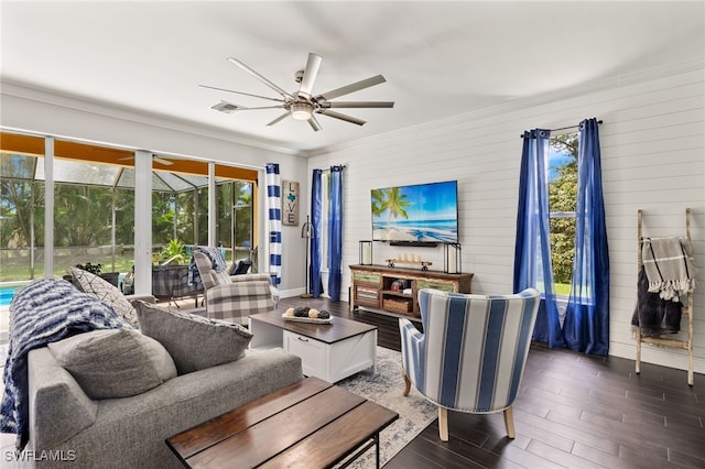 living room with wood walls, ceiling fan, and ornamental molding