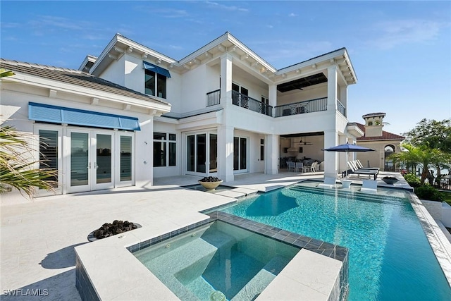 rear view of property featuring french doors, a patio area, and a swimming pool with hot tub