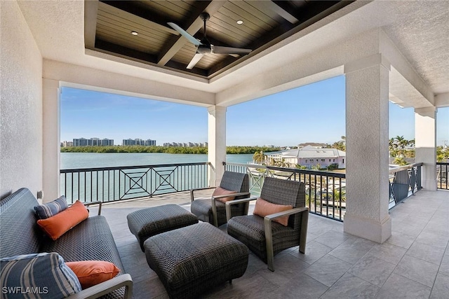 view of patio featuring ceiling fan, a water view, and a balcony