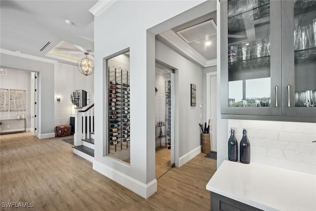 interior space with wood-type flooring, a raised ceiling, a chandelier, and ornamental molding