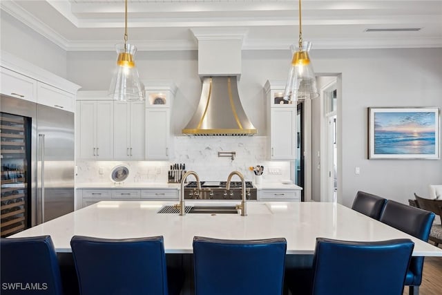 kitchen with white cabinets, a kitchen breakfast bar, an island with sink, and pendant lighting