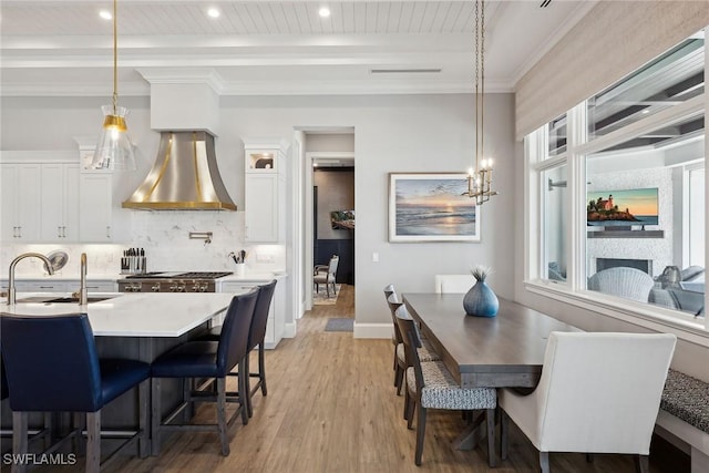 dining room with sink, light wood-type flooring, and beamed ceiling