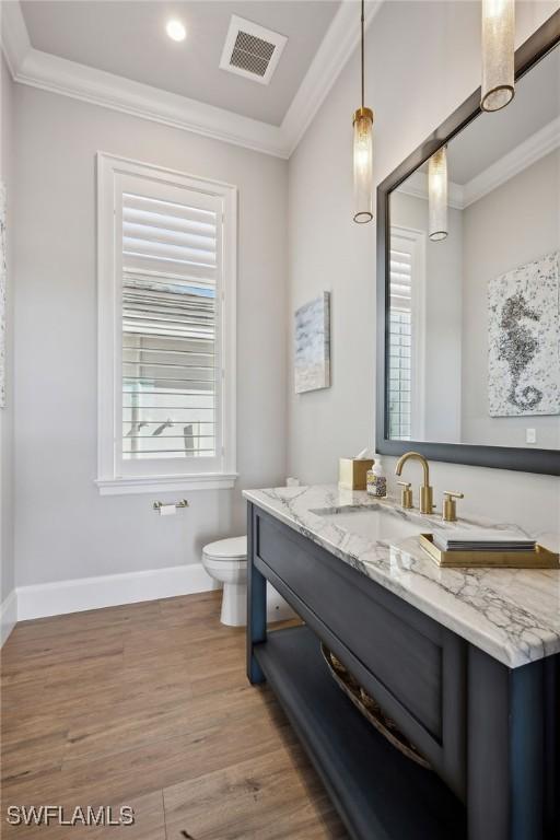 bathroom with toilet, vanity, hardwood / wood-style floors, and crown molding