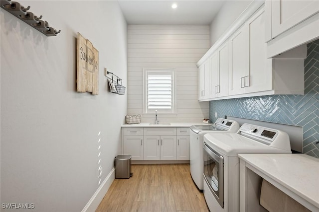 laundry area featuring washer and dryer, cabinets, light hardwood / wood-style floors, and sink