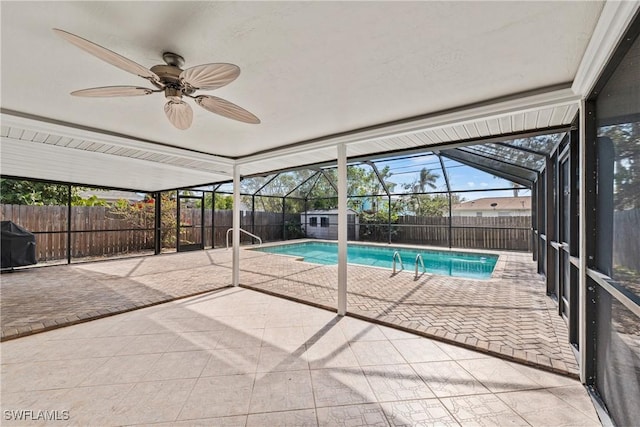 view of pool with grilling area, a patio, ceiling fan, and glass enclosure