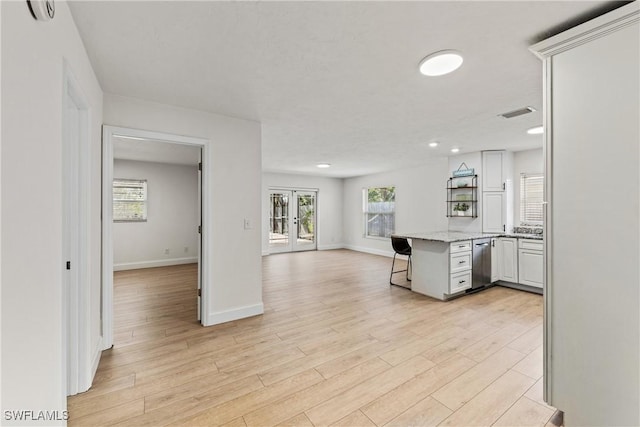 kitchen featuring a breakfast bar, light hardwood / wood-style floors, white cabinets, french doors, and kitchen peninsula