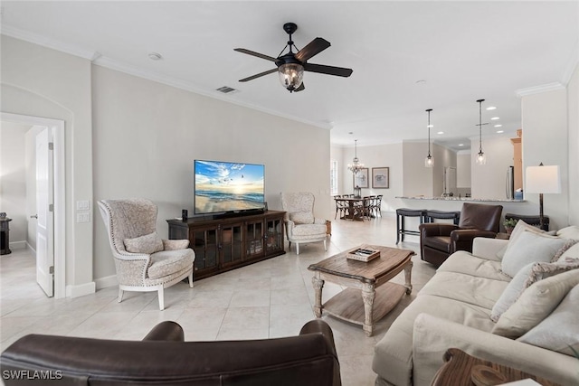 tiled living room featuring crown molding and ceiling fan with notable chandelier