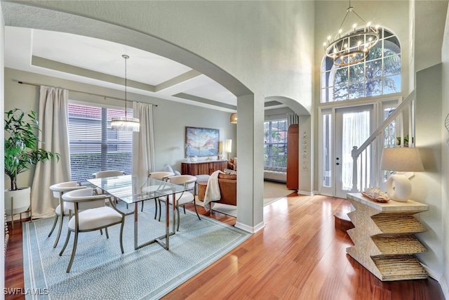 dining area featuring hardwood / wood-style floors, a towering ceiling, and a notable chandelier