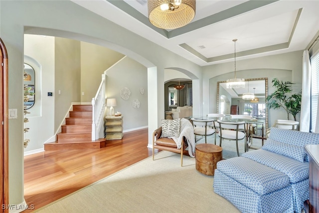 sitting room with a tray ceiling, hardwood / wood-style floors, and a chandelier