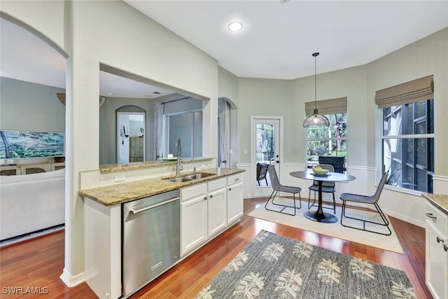 kitchen featuring light stone countertops, stainless steel dishwasher, sink, decorative light fixtures, and white cabinetry