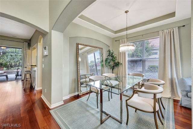 dining space featuring a notable chandelier, dark hardwood / wood-style floors, and a tray ceiling