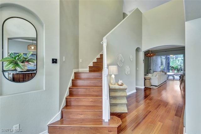 stairway featuring wood-type flooring and a towering ceiling