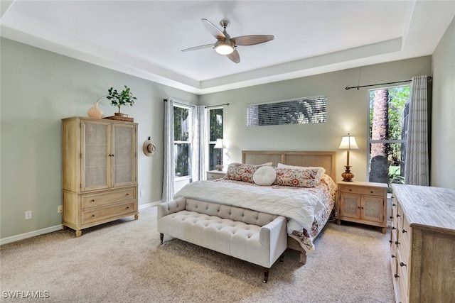 carpeted bedroom with a tray ceiling and ceiling fan