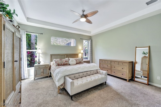 bedroom featuring a closet, a tray ceiling, ceiling fan, and light colored carpet