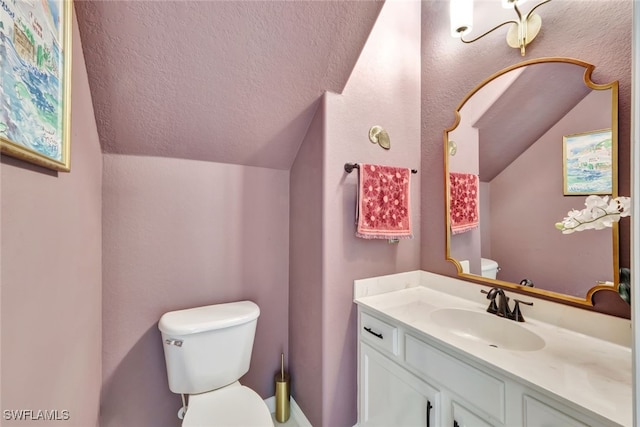 bathroom with vanity, vaulted ceiling, and toilet