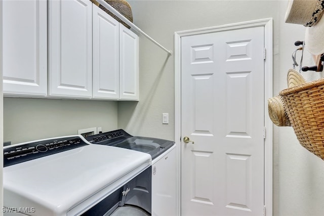 clothes washing area with washer and clothes dryer and cabinets