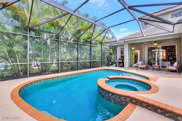 view of swimming pool with an in ground hot tub, glass enclosure, ceiling fan, and a patio area