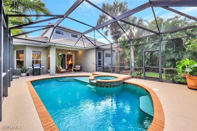 view of pool featuring glass enclosure, ceiling fan, grilling area, an in ground hot tub, and a patio