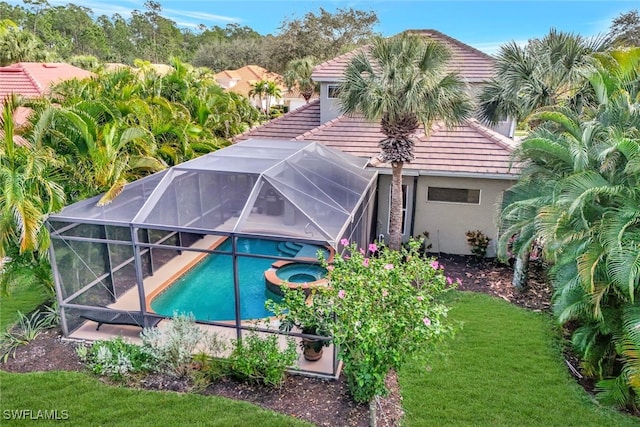 view of pool featuring glass enclosure and an in ground hot tub