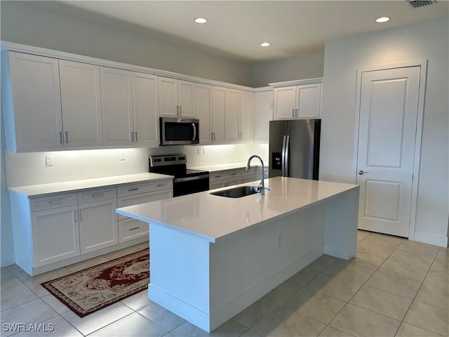 kitchen featuring sink, stainless steel appliances, white cabinets, a center island with sink, and light tile patterned flooring