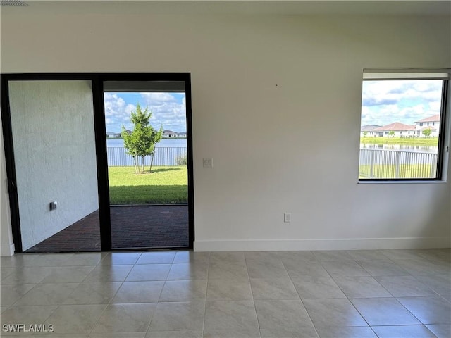 spare room with a water view and light tile patterned flooring