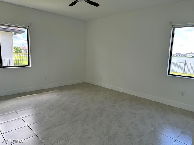 spare room with ceiling fan, a healthy amount of sunlight, and light tile patterned flooring