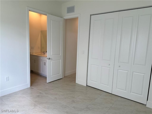 unfurnished bedroom featuring ensuite bath, a closet, and sink