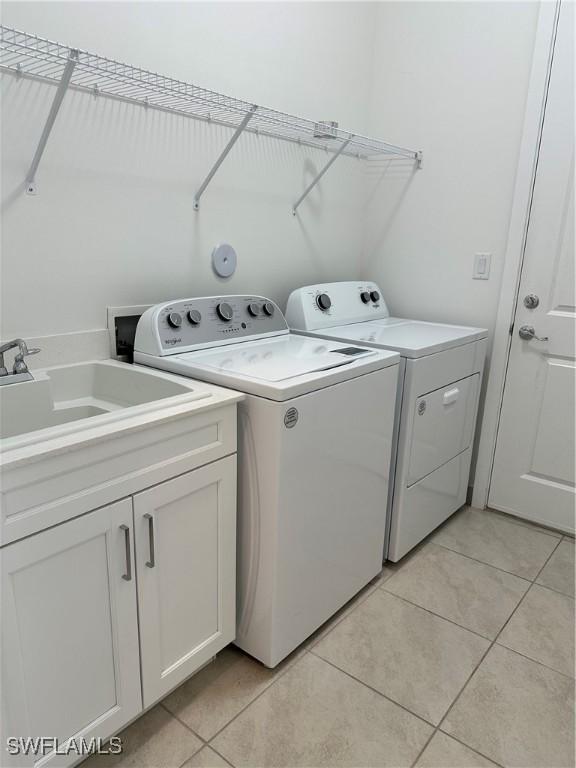 washroom with light tile patterned flooring, cabinets, independent washer and dryer, and sink