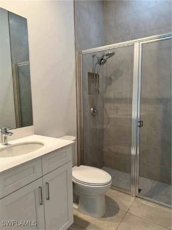 bathroom featuring tile patterned floors, toilet, vanity, and walk in shower