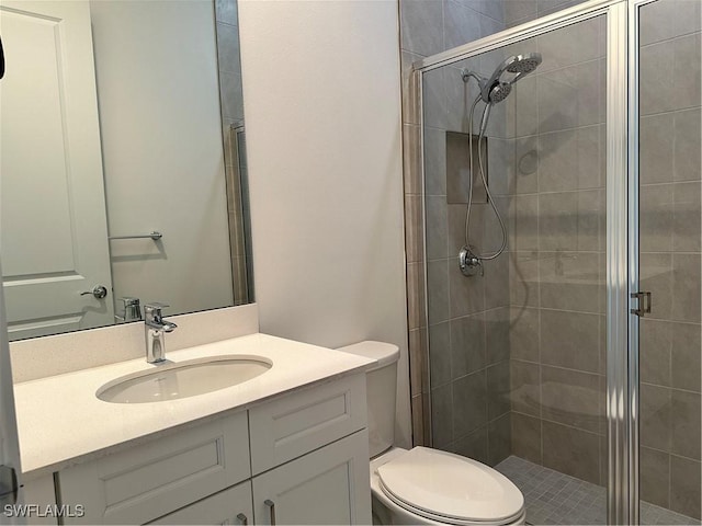 bathroom with vanity, toilet, and a shower with door