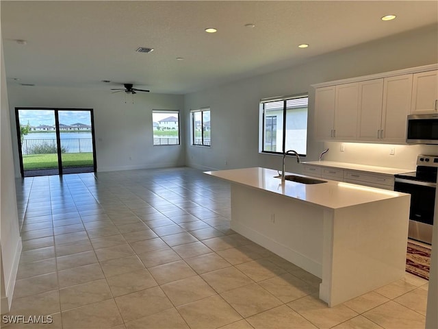 kitchen with a kitchen island with sink, sink, appliances with stainless steel finishes, light tile patterned flooring, and white cabinetry