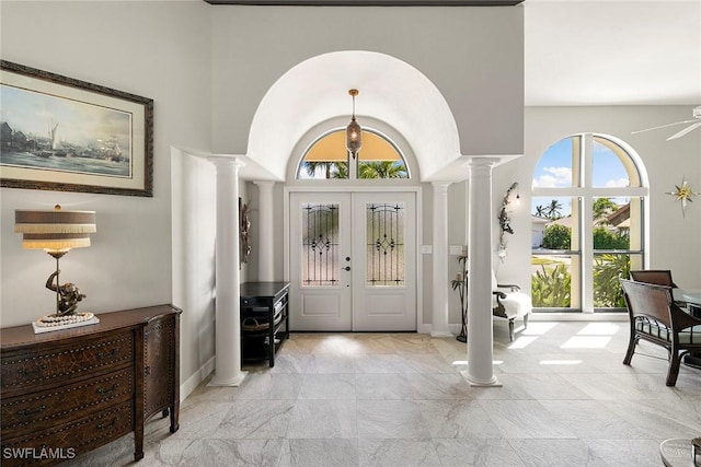 entryway featuring ornate columns, a towering ceiling, and french doors