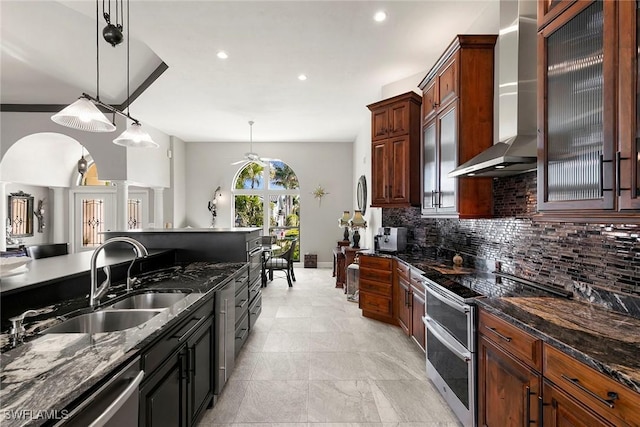 kitchen featuring sink, pendant lighting, wall chimney range hood, and appliances with stainless steel finishes