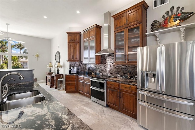 kitchen with appliances with stainless steel finishes, backsplash, wall chimney exhaust hood, sink, and dark stone countertops