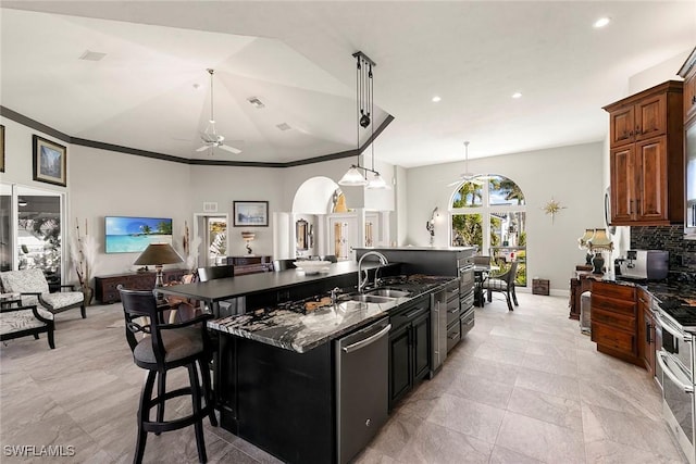 kitchen featuring a large island with sink, dark stone counters, sink, stainless steel dishwasher, and a kitchen bar