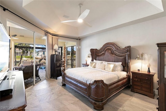 bedroom with ceiling fan, access to exterior, and a tray ceiling