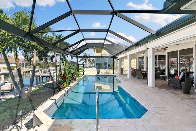 view of pool with a patio, a water view, glass enclosure, and ceiling fan