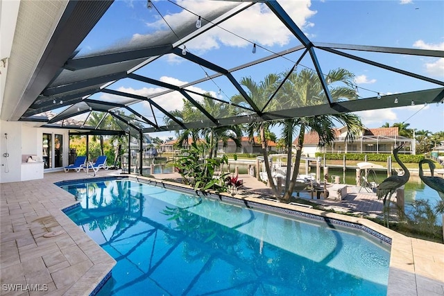 view of pool with a lanai, a patio area, and a water view