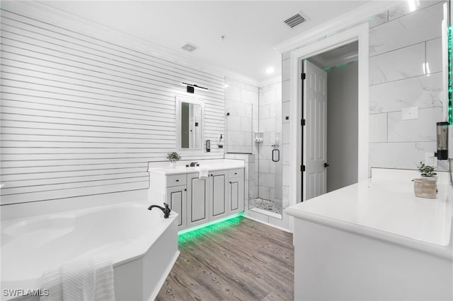 bathroom with wood-type flooring, vanity, tile walls, ornamental molding, and separate shower and tub