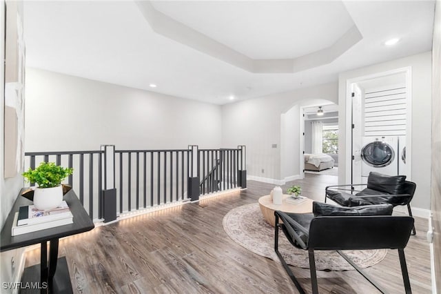 living area featuring hardwood / wood-style floors, a raised ceiling, and washing machine and clothes dryer