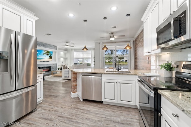 kitchen with decorative light fixtures, ceiling fan, sink, stainless steel appliances, and white cabinets