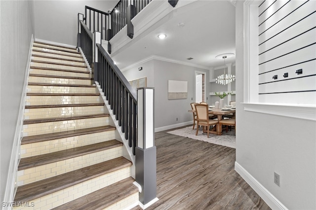 staircase featuring wood-type flooring, crown molding, and a chandelier