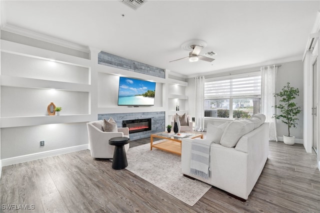 living room with ceiling fan, built in shelves, ornamental molding, and hardwood / wood-style flooring