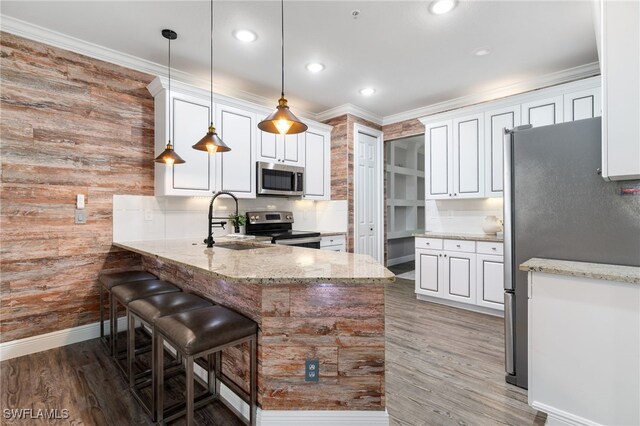 1330 Mariposa Cir Unit 103, Naples, FL 34105 - kitchen with white cabinets, a peninsula, a sink, light stone countertops, and appliances with stainless steel finishes
