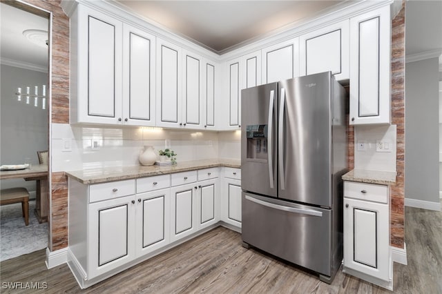 kitchen with stainless steel fridge with ice dispenser, white cabinetry, light hardwood / wood-style floors, and light stone counters