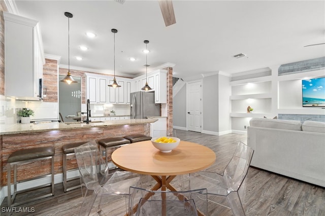 dining space with crown molding, sink, dark hardwood / wood-style floors, and built in shelves